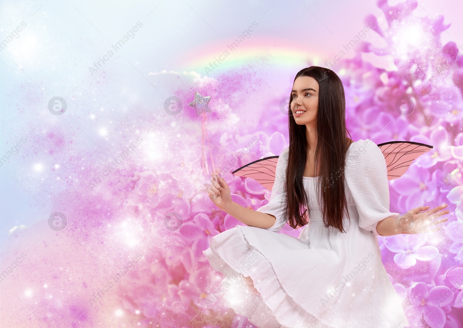 Image of Ethereal fairy holding magic wand among lilac flowers. Beautiful girl with wings