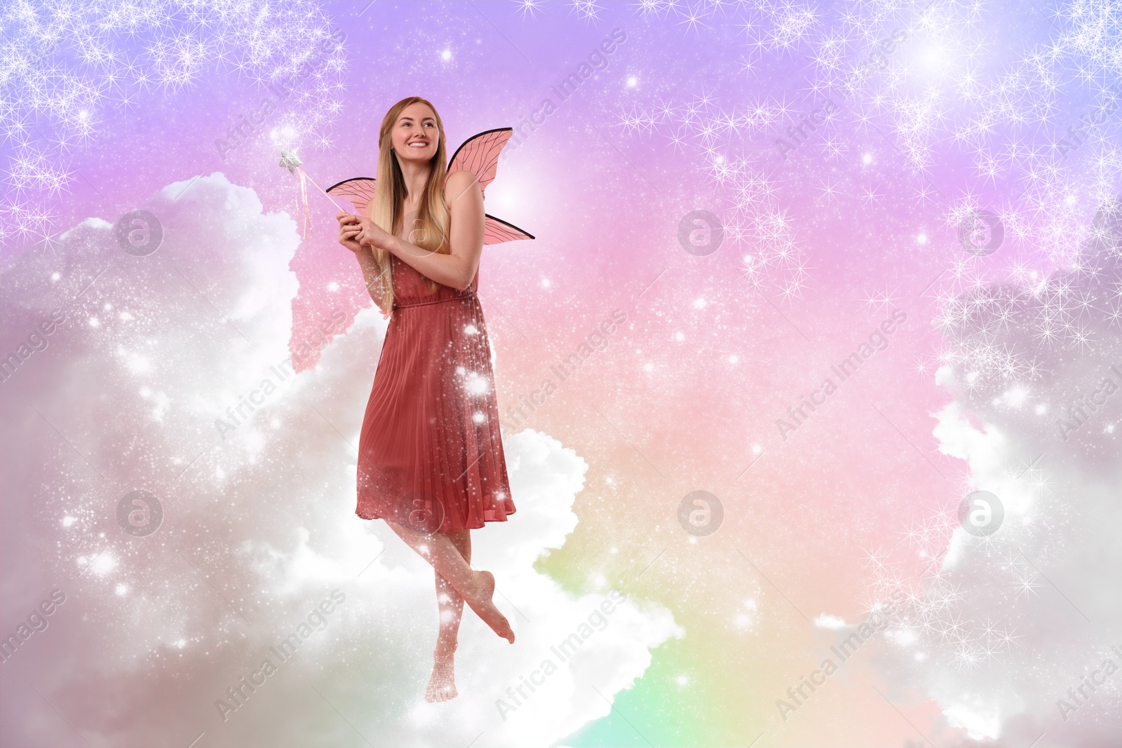 Image of Ethereal fairy casting enchanted lights with magic wand among fluffy clouds in colorful sky. Beautiful girl with wings