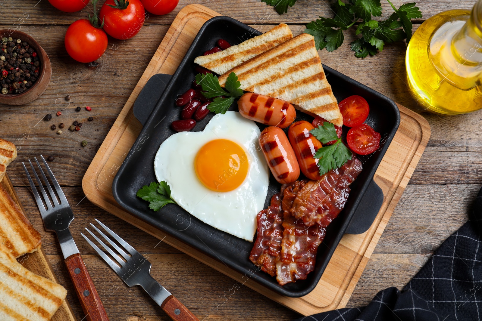 Photo of Delicious breakfast with heart shaped fried egg and  sausages served on wooden table, flat lay