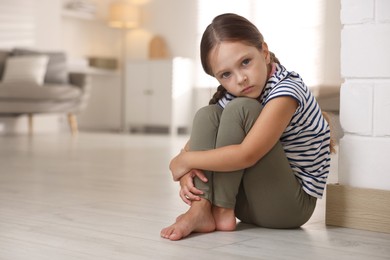 Photo of Orphanage concept. Sad girl sitting on floor indoors