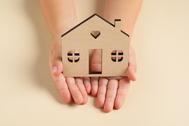 Photo of Adoption concept. Kid with cutout of house at beige table, closeup