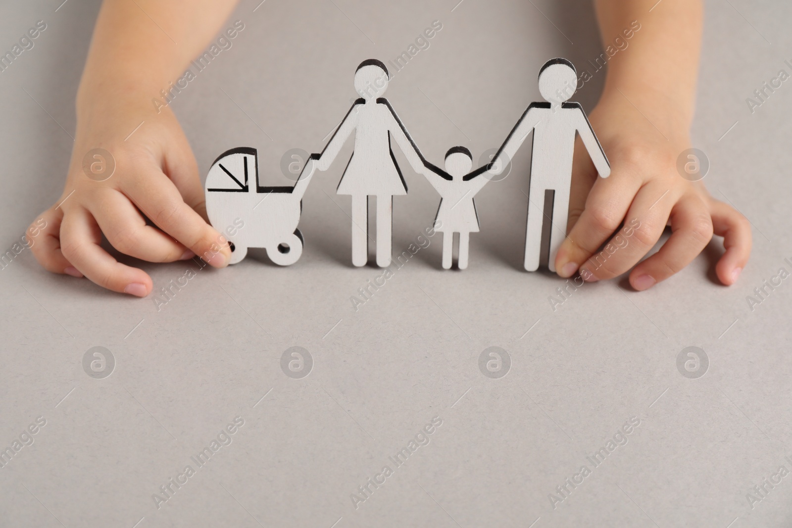 Photo of Adoption concept. Kid with cutout of family at light grey background, closeup. Space for text