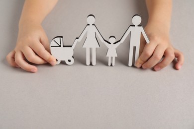 Photo of Adoption concept. Kid with cutout of family at light grey background, closeup. Space for text