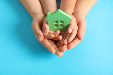 Photo of Adoption concept. Woman and kid with cutout of house at light blue background, top view