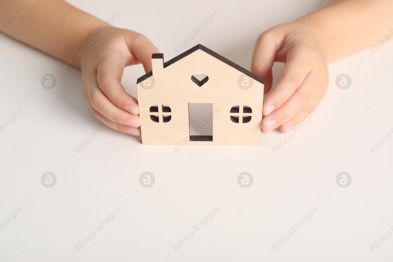 Photo of Adoption concept. Kid with cutout of house at white table, closeup. Space for text