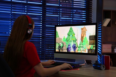 Girl playing video game with keyboard and mouse at table in dark room