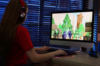 Photo of Girl playing video game with keyboard and mouse at table in dark room