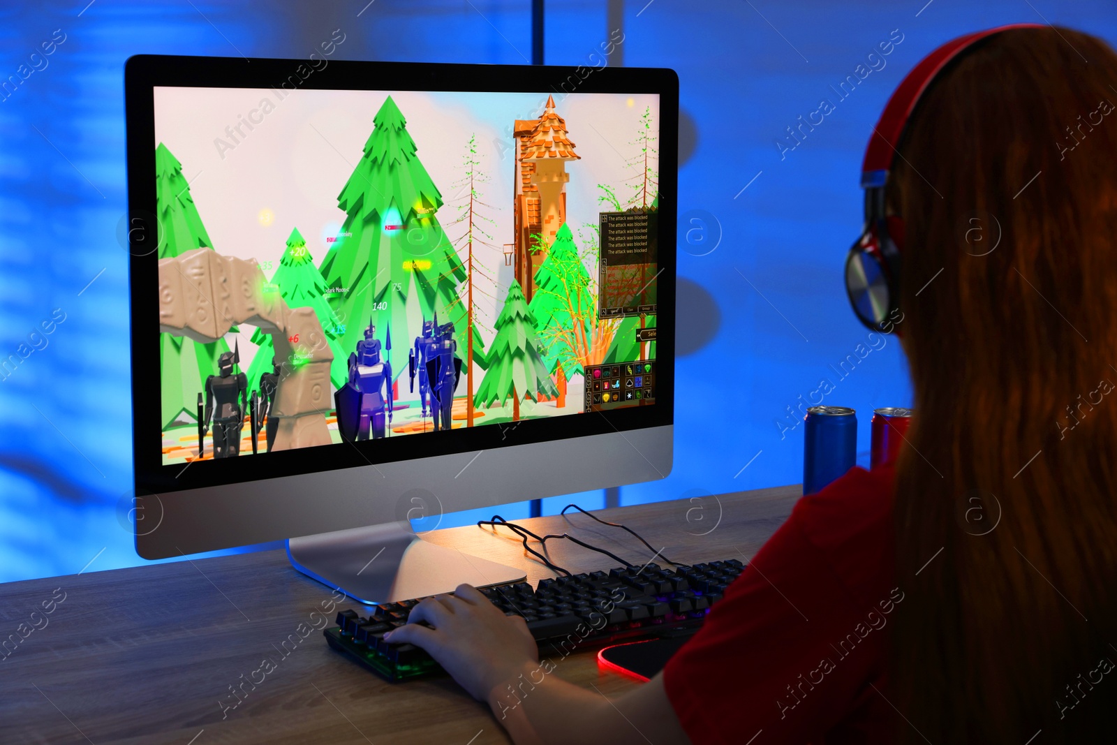 Photo of Girl playing video game with keyboard at wooden table in dark room