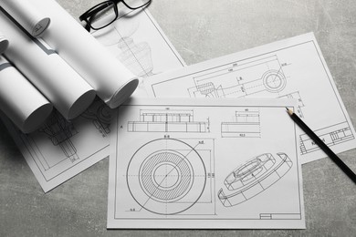 Photo of Different engineering drawings, glasses and pencil on gray textured table, flat lay