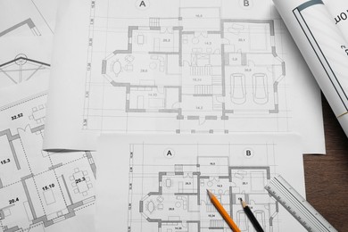 Photo of Different architectural drawings, ruler and pencils on wooden table, top view