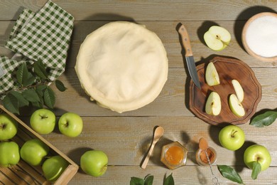 Photo of Raw homemade apple pie and ingredients on wooden table, flat lay