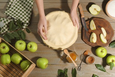 Photo of Woman making homemade apple pie at wooden table, top view