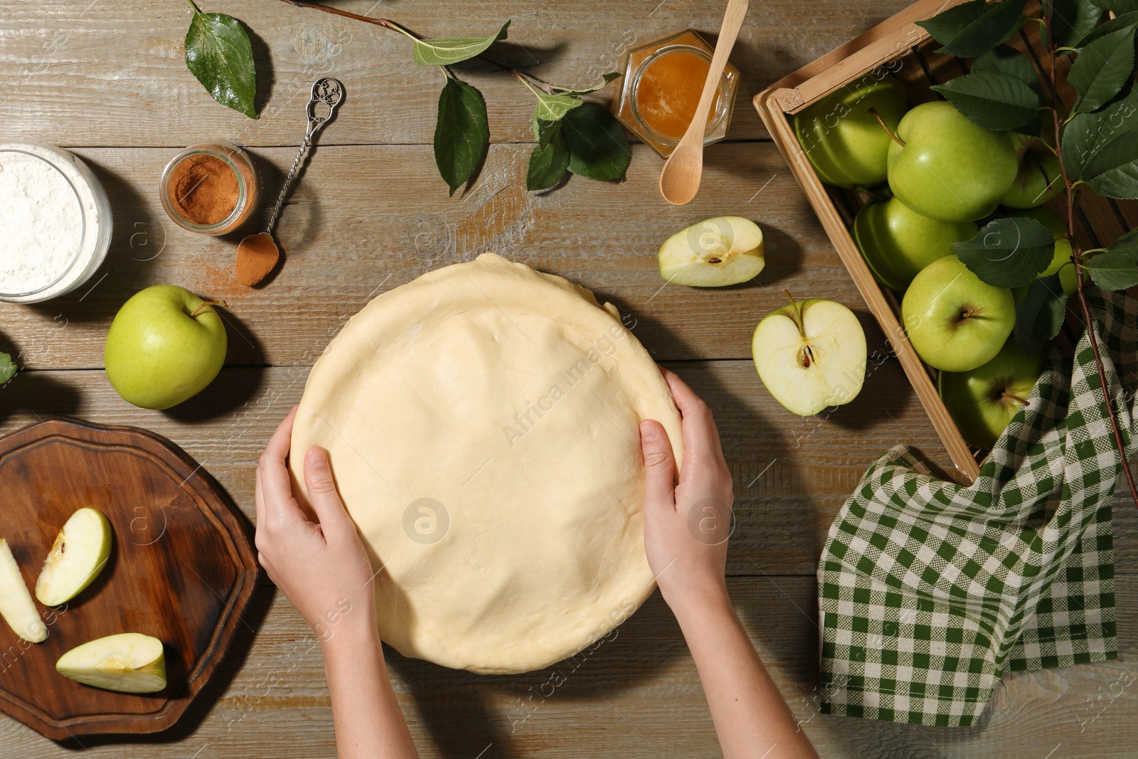 Photo of Woman making homemade apple pie at wooden table, top view