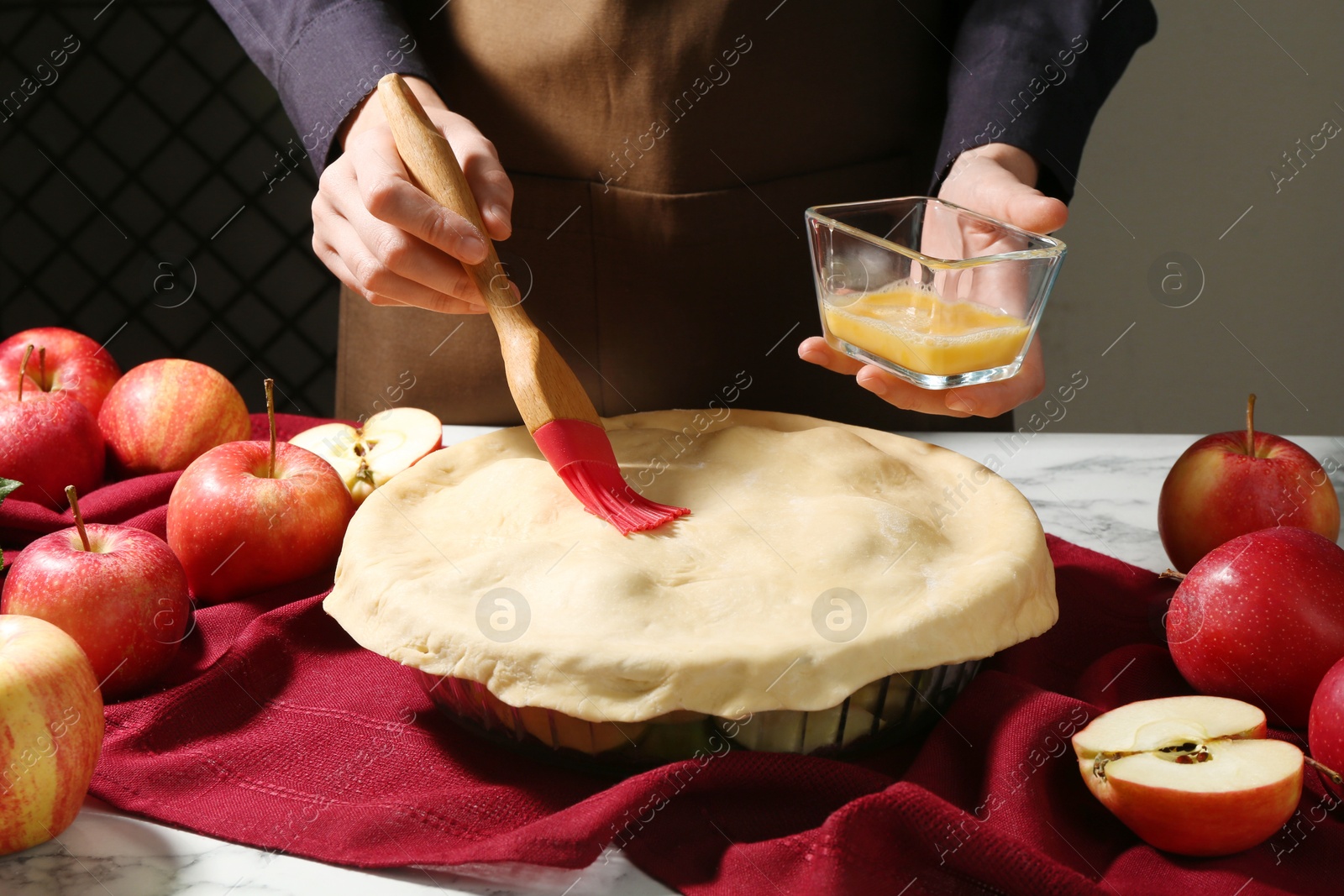 Photo of Woman making homemade apple pie at white marble table, closeup