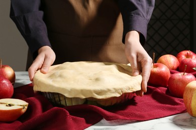 Photo of Woman making homemade apple pie at white marble table, closeup