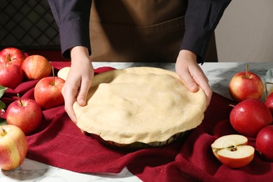 Photo of Woman making homemade apple pie at white marble table, closeup