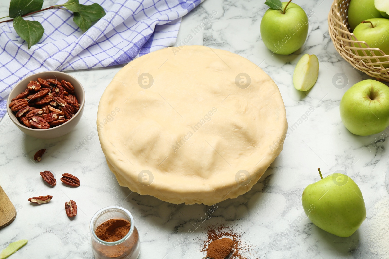 Photo of Raw homemade apple pie and ingredients on white marble table