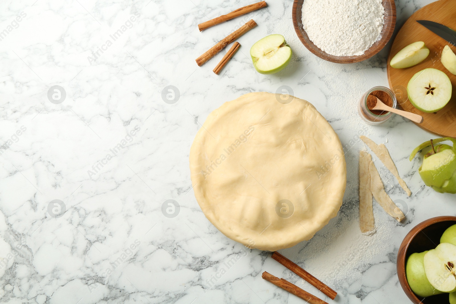 Photo of Flat lay composition with raw homemade apple pie and ingredients on white marble table. Space for text