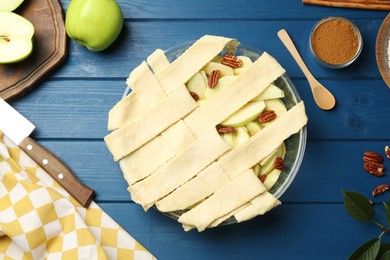 Photo of Flat lay composition with raw homemade apple pie and ingredients on blue wooden table