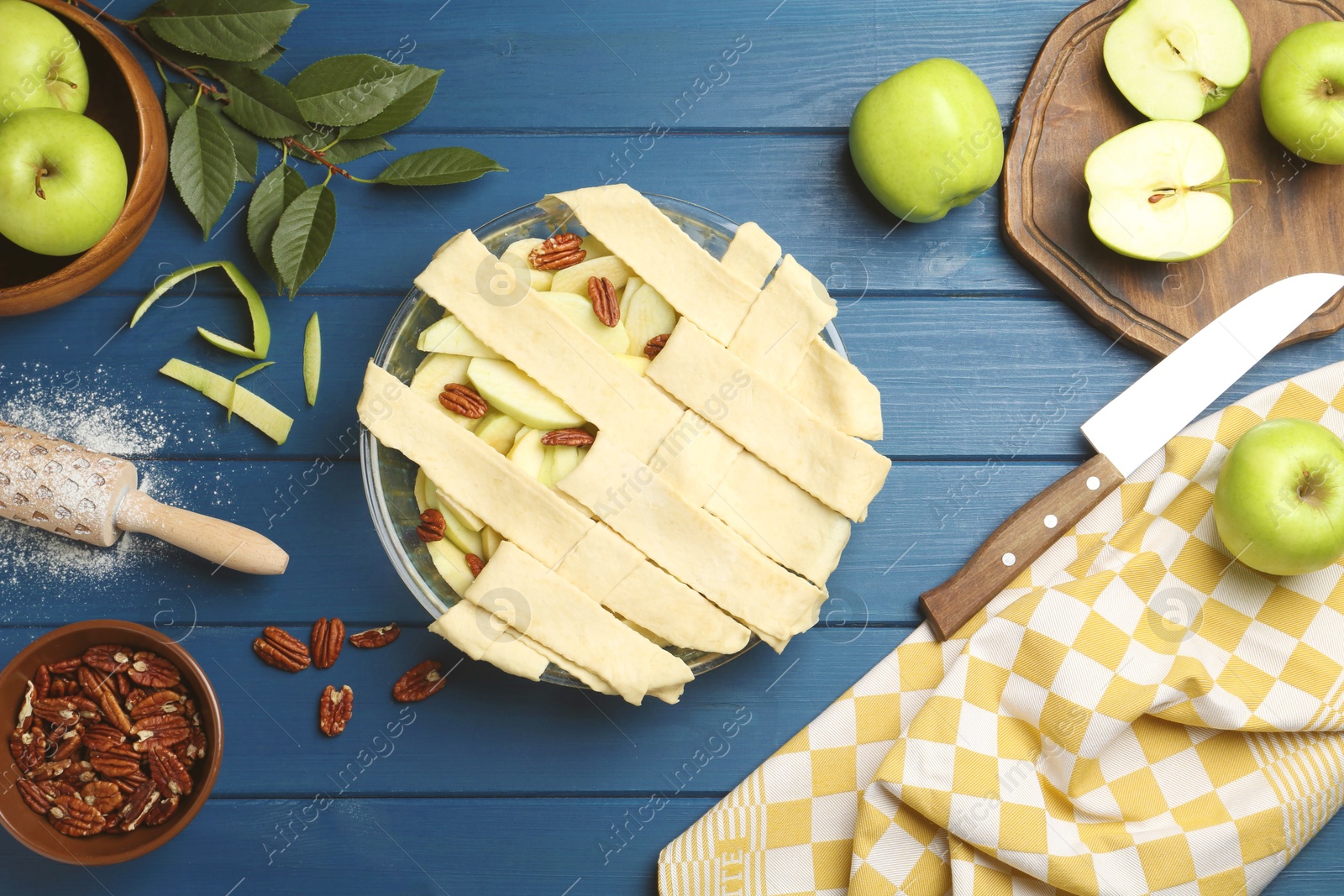 Photo of Flat lay composition with raw homemade apple pie and ingredients on blue wooden table