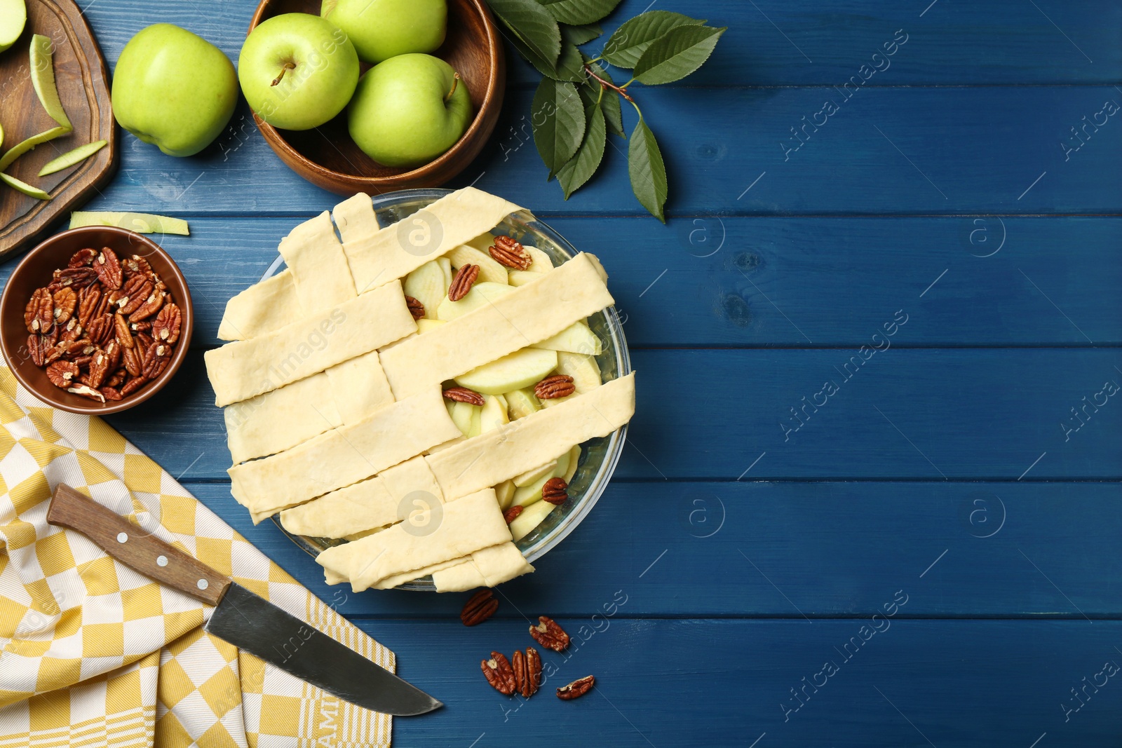 Photo of Flat lay composition with raw homemade apple pie and ingredients on blue wooden table. Space for text