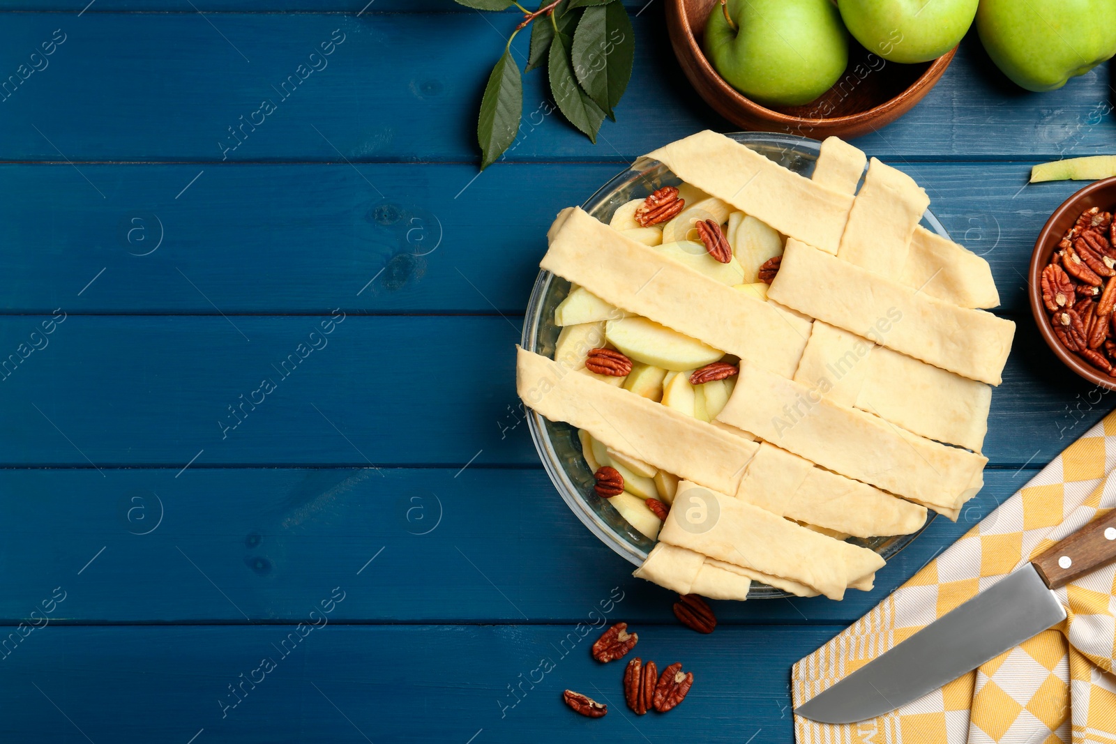 Photo of Flat lay composition with raw homemade apple pie and ingredients on blue wooden table. Space for text