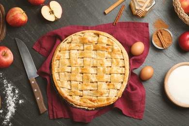 Photo of Flat lay composition with tasty homemade apple pie and ingredients on dark textured table