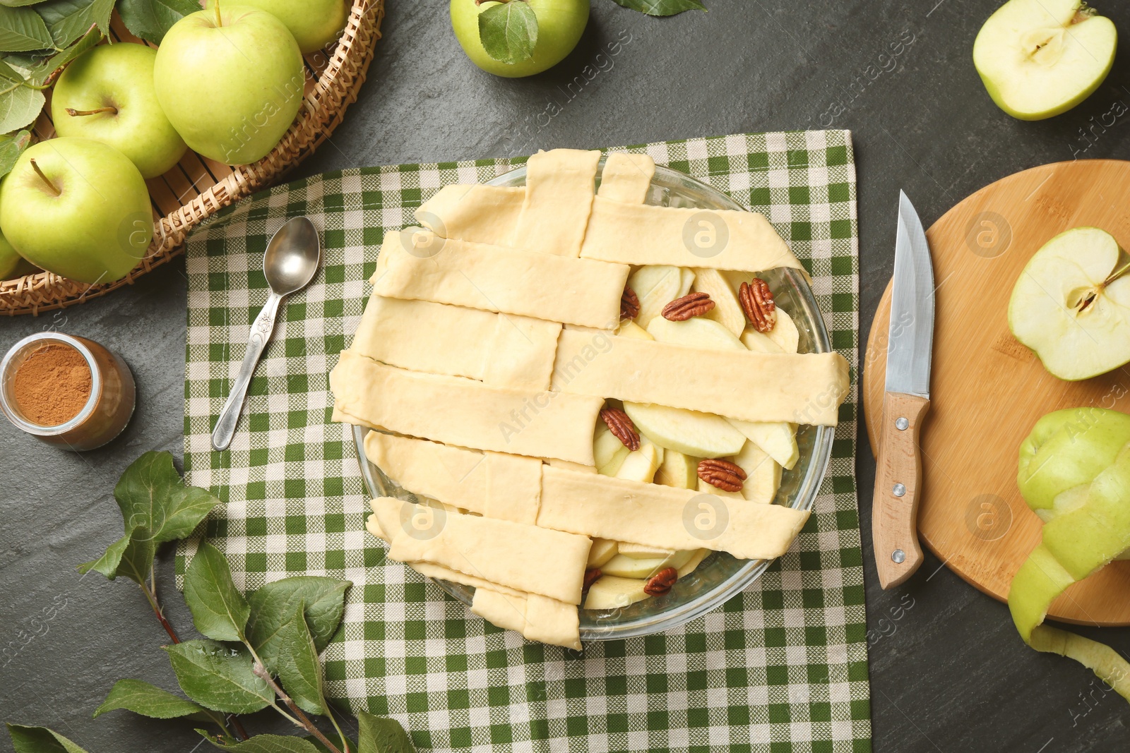 Photo of Flat lay composition with raw homemade apple pie and ingredients on dark textured table