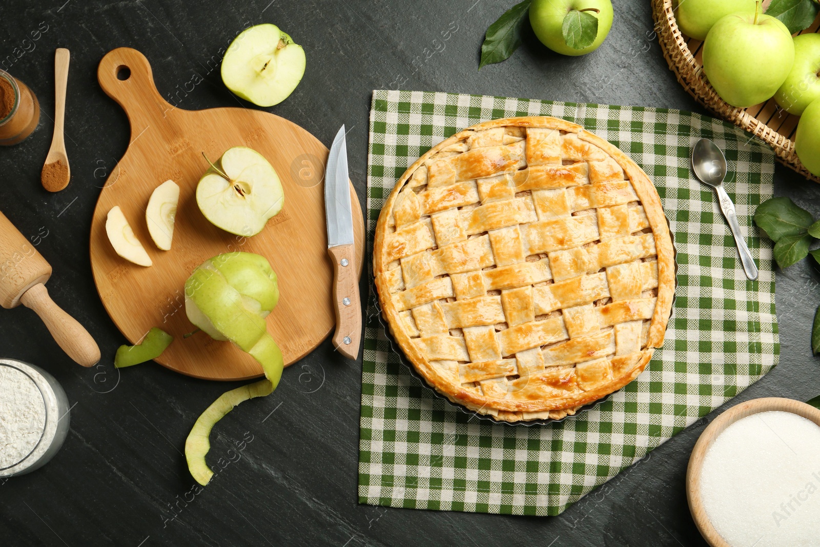 Photo of Flat lay composition with tasty homemade apple pie and ingredients on dark textured table