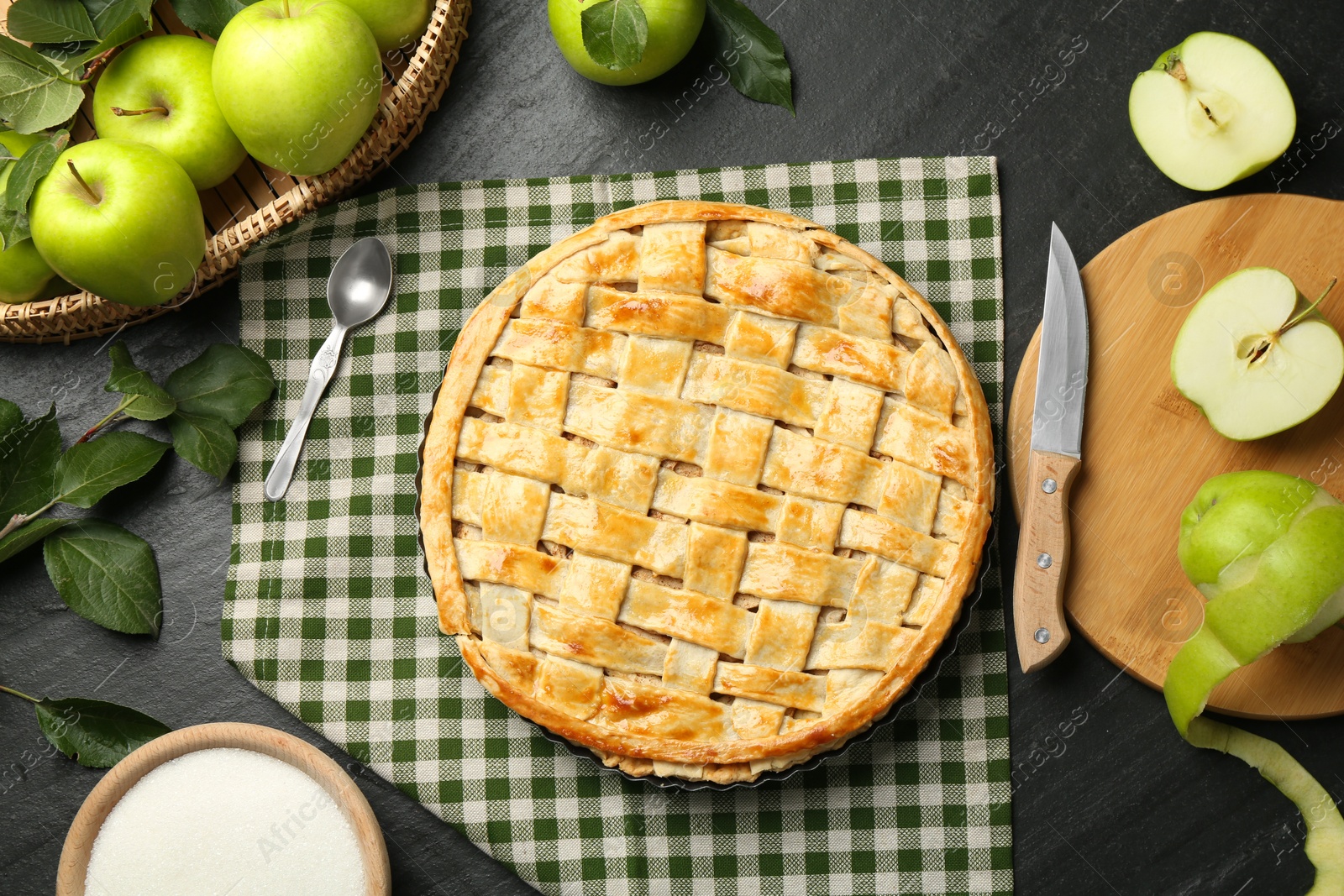 Photo of Flat lay composition with tasty homemade apple pie and ingredients on dark textured table