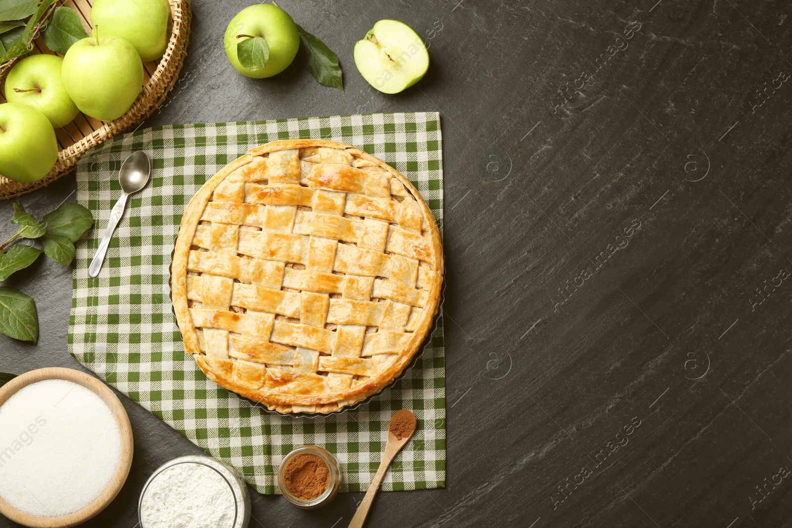 Photo of Flat lay composition with tasty homemade apple pie and ingredients on dark textured table. Space for text