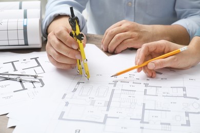 Photo of Architects working with project, closeup. Different technical drawings on wooden table