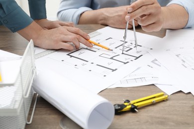 Photo of Architects working with project, closeup. Different technical drawings on wooden table