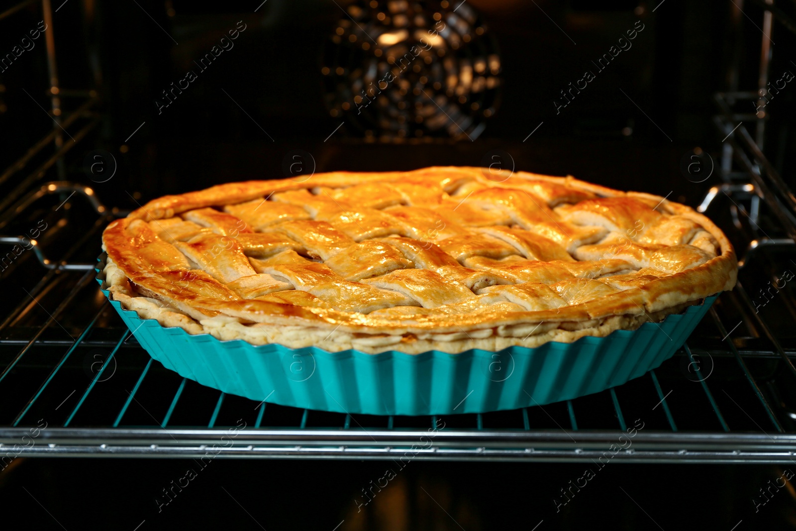 Photo of Baking dish with homemade apple pie in oven, closeup