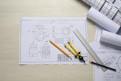 Photo of Different engineering drawings, pencils, ruler and divider on wooden table, flat lay