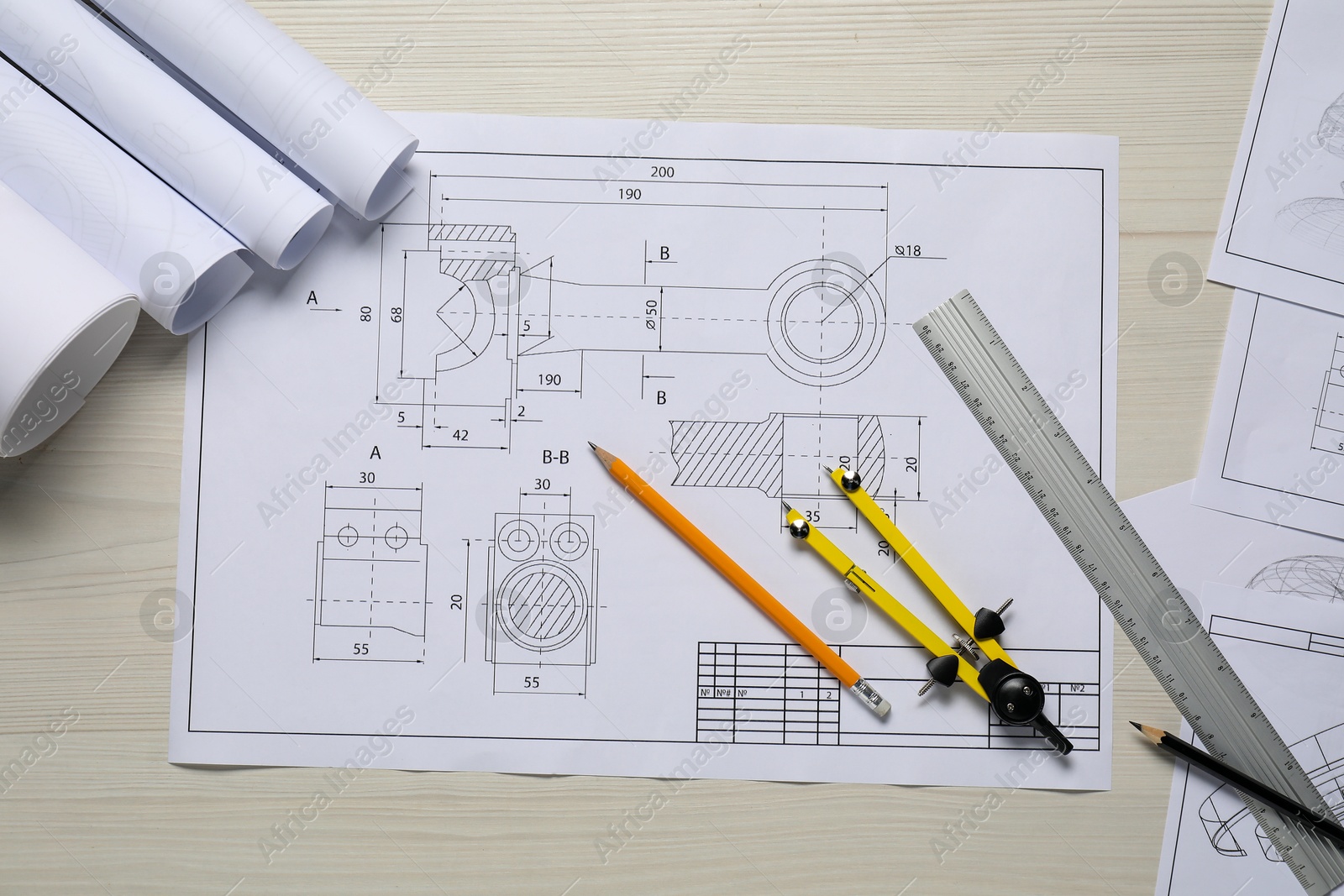 Photo of Different engineering drawings, pencils, ruler and divider on wooden table, flat lay