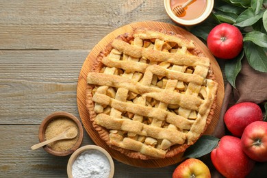 Photo of Flat lay composition with tasty homemade apple pie and ingredients on wooden table