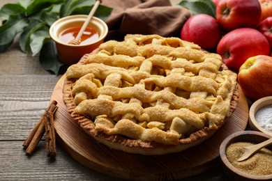 Photo of Tasty homemade apple pie and ingredients on wooden table, closeup