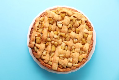 Photo of Tasty homemade apple pie on light blue background, top view