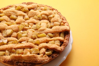 Photo of Tasty homemade apple pie on yellow background, closeup. Space for text