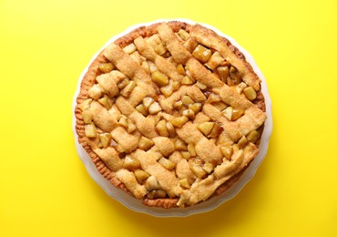 Photo of Tasty homemade apple pie on yellow background, top view