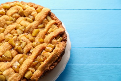 Photo of Tasty homemade apple pie on light blue wooden table. Space for text