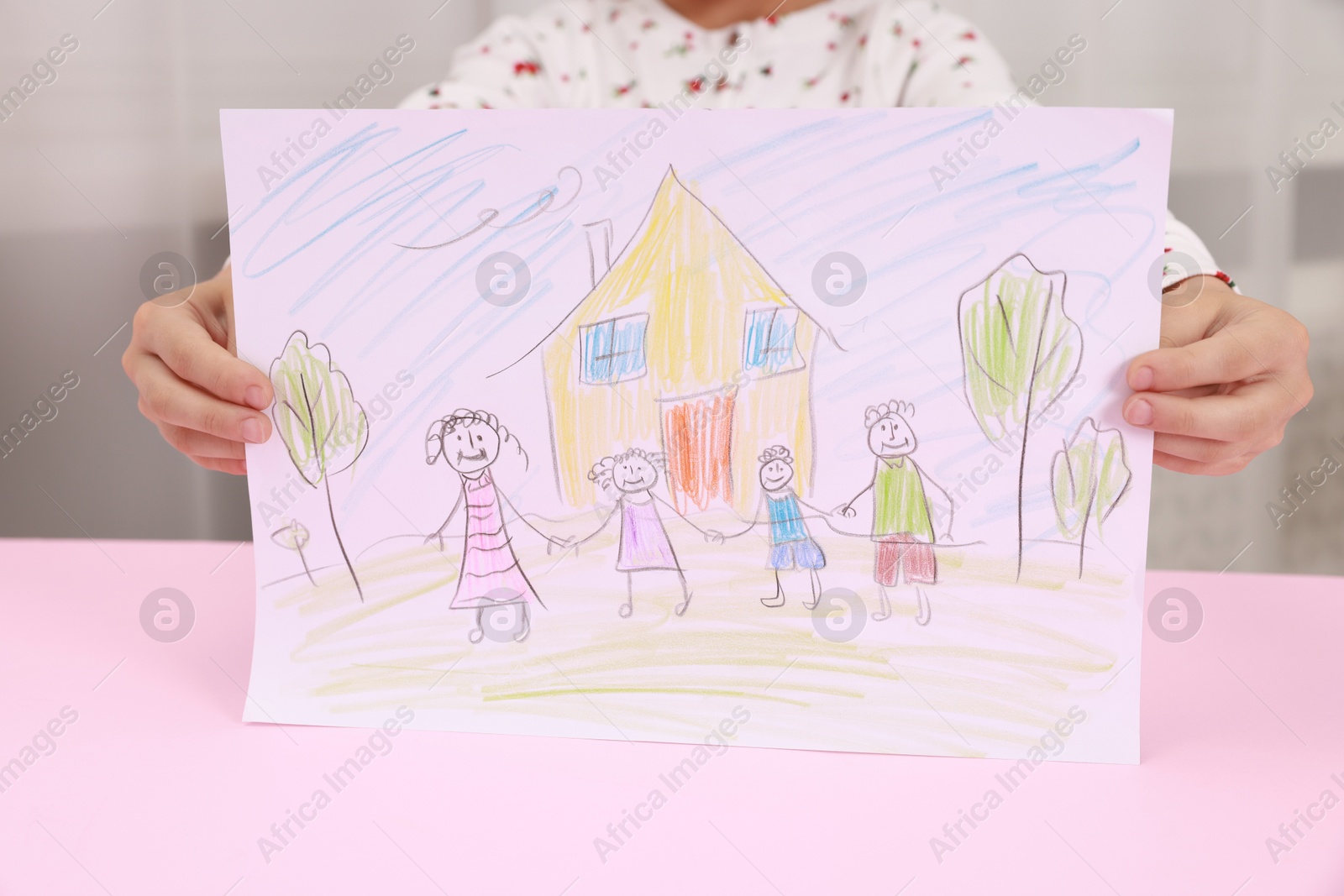 Photo of Adoption. Little girl holding drawing of family at pink table, closeup