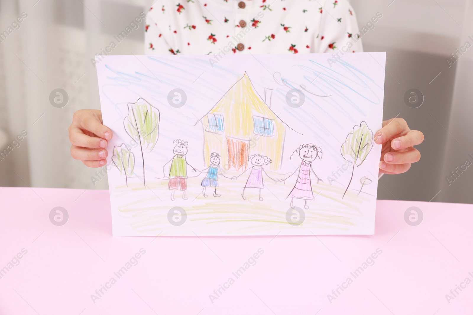 Photo of Adoption. Little girl holding drawing of family at pink table, closeup