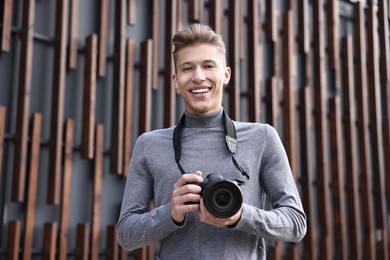 Photo of Professional photographer with modern camera near wall outdoors