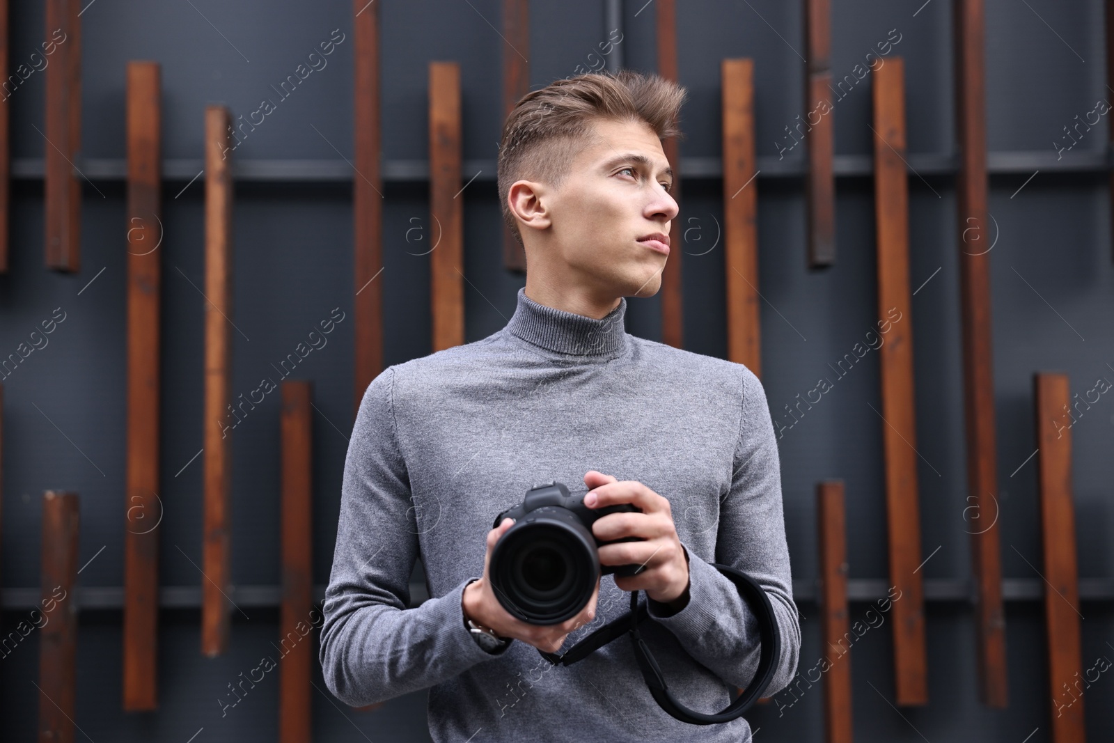 Photo of Professional photographer with modern camera near wall outdoors