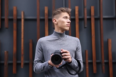 Photo of Professional photographer with modern camera near wall outdoors