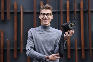 Photo of Professional photographer with modern camera near wall outdoors