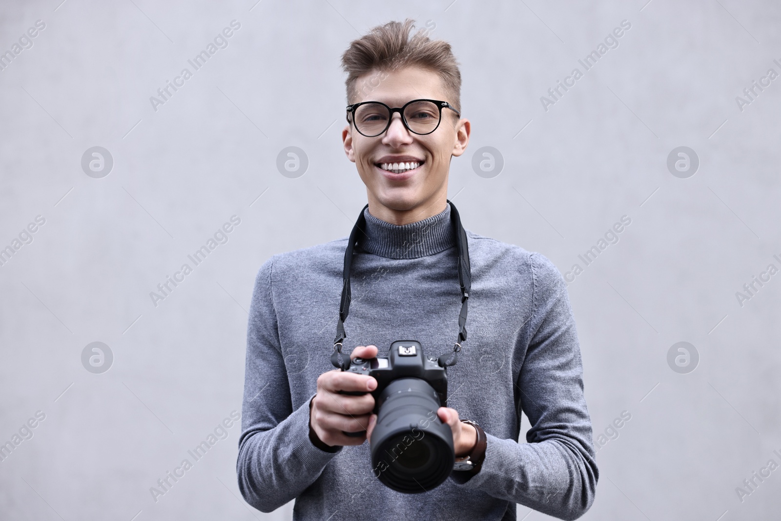 Photo of Professional photographer with camera near grey wall outdoors