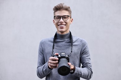 Photo of Professional photographer with camera near grey wall outdoors